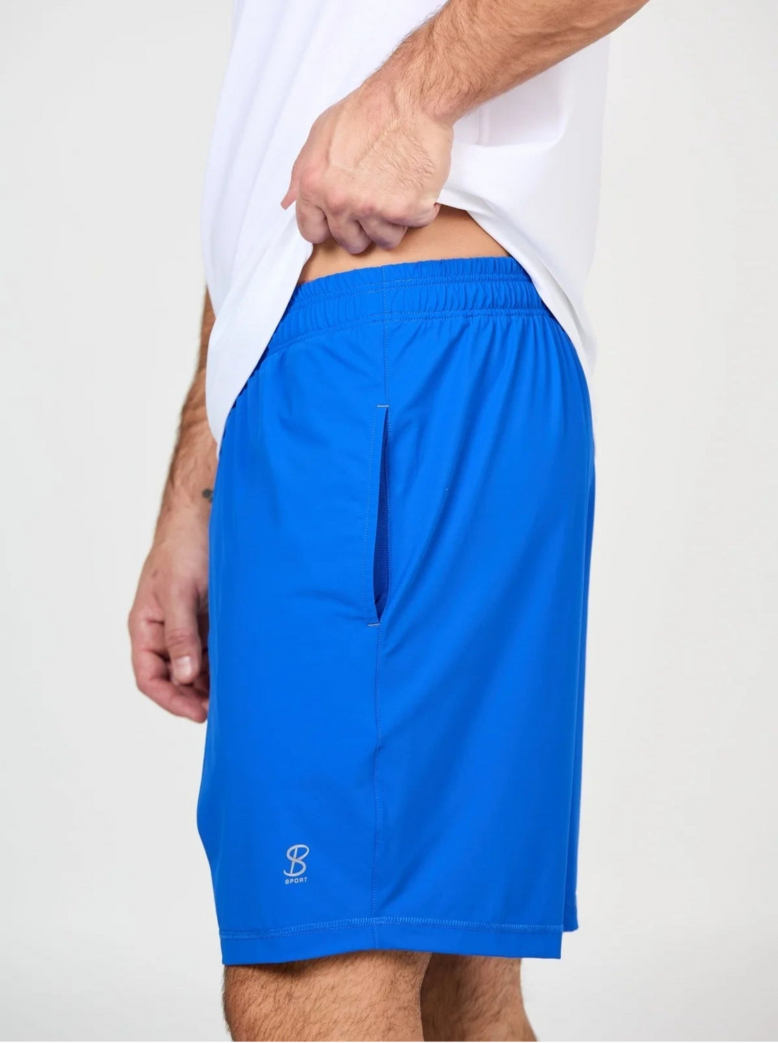 Person wearing blue shorts and a white shirt on a plain background