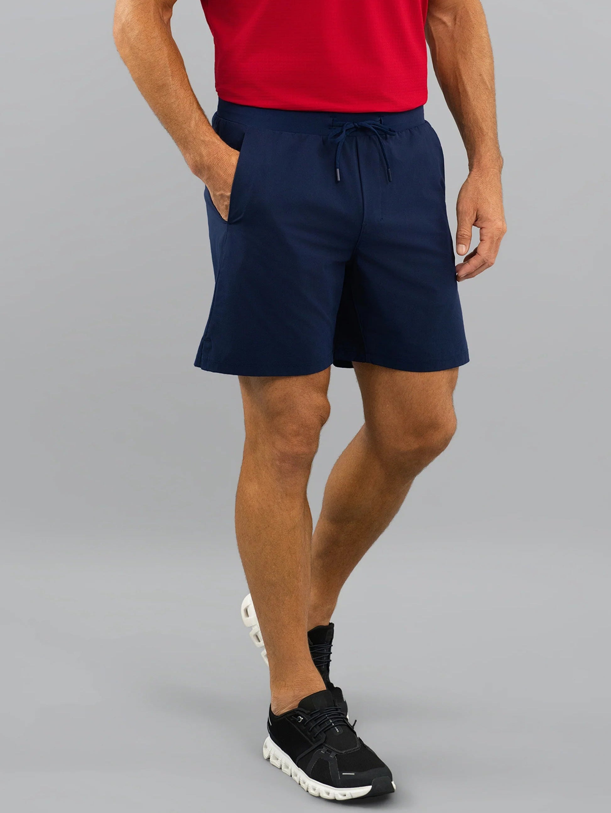 Person wearing navy shorts and a red shirt on a gray background