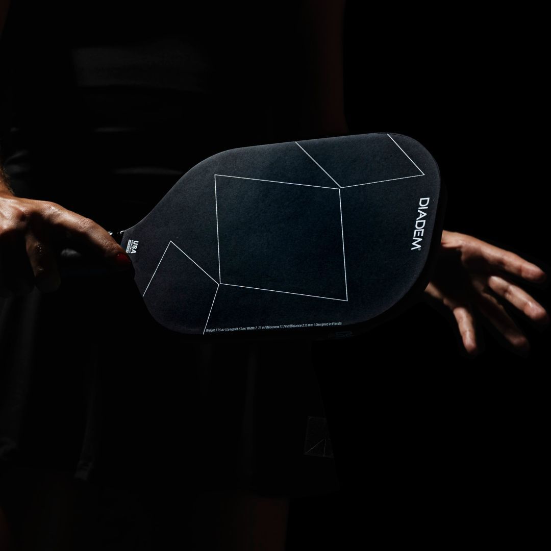 Person holding a black paddle with geometric design and 'Diadem' branding against a dark background